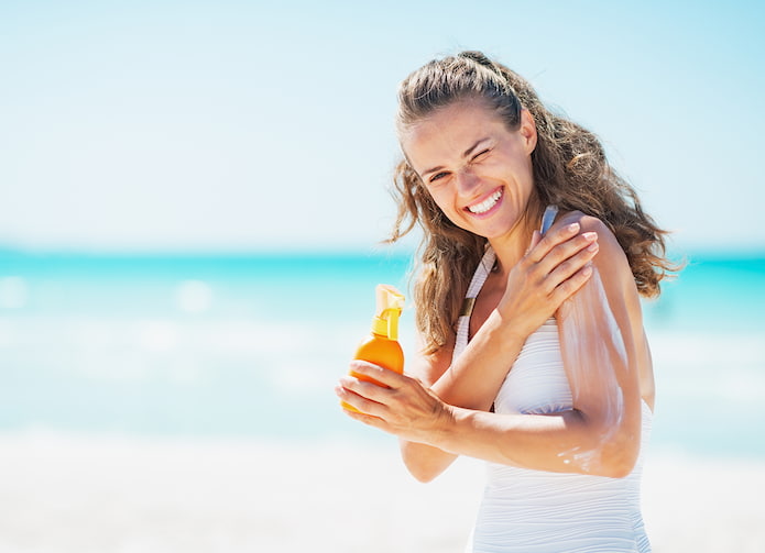 woman putting sun lotion on her skin