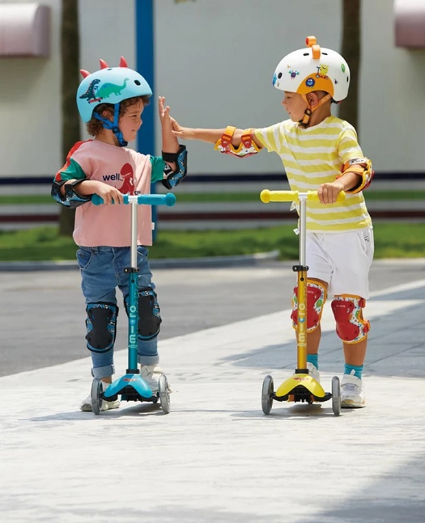 picture of two kids riding with helmets in park