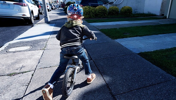 picture of a kid riding a bike on the sideroad with helmet 