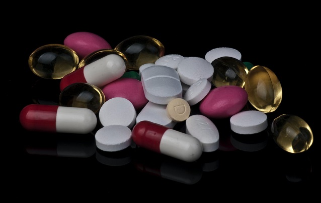 picture of assorted pills and tablets pilled on black surface 