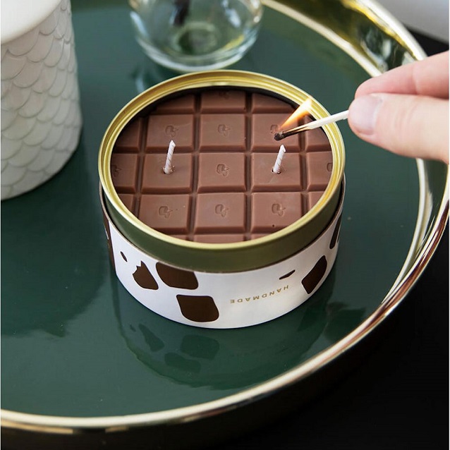 lighting a chocolate scented candle on table