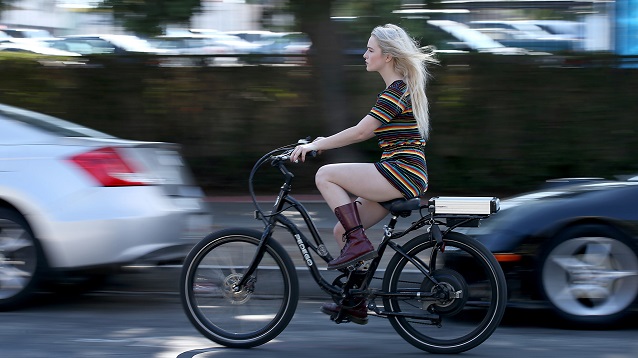 girl riding an electric bicycle through traffic  