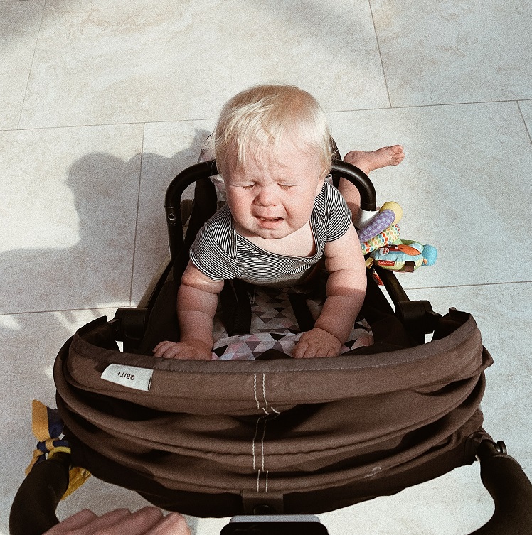 picture of a crying baby in a stroller outside 