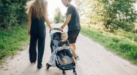 picture of a woman and a man walking in nature with a baby in a stroller