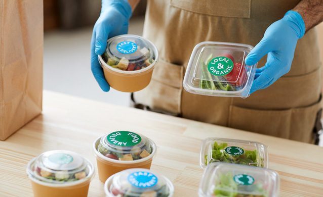 Man wearing gloves packs organic food in plastic boxes