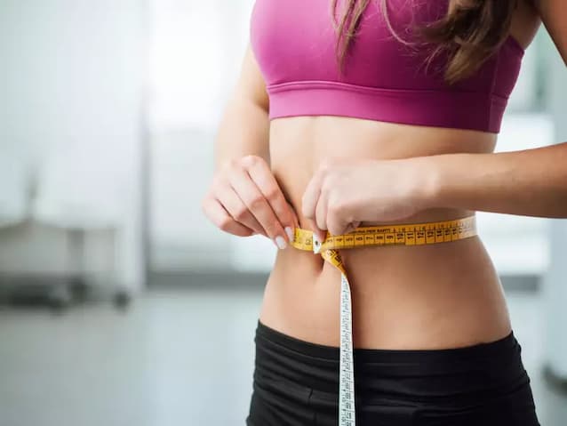 fit girl measuring how much fat she lost