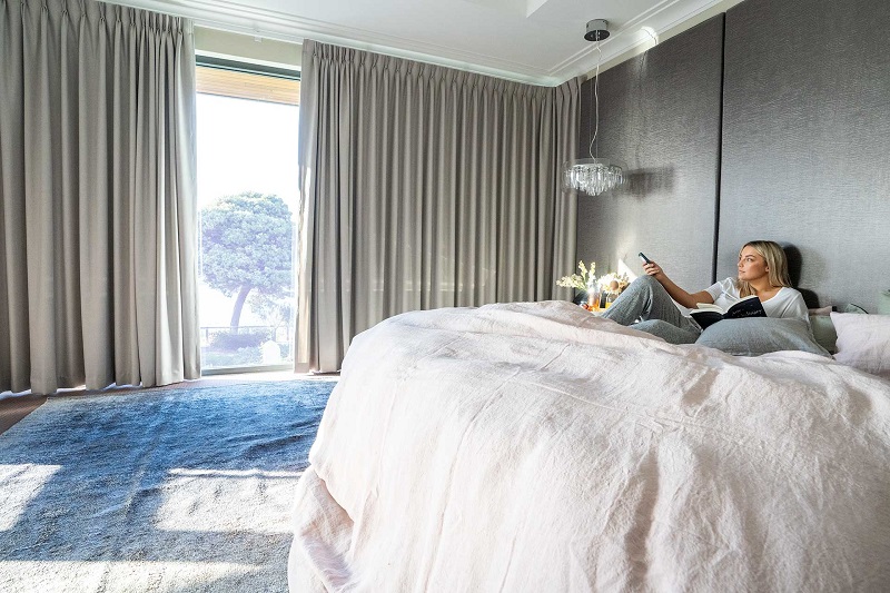 woman on a bed opening motorised blinds