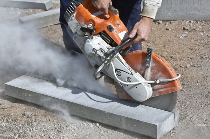 A person using his concrete cutting saw to cut down a piece of concrete