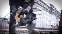 A person holding a concrete cutting saw while wated is dripping from the blades