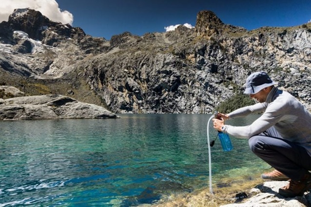 person using survival water filtration systems outdoors